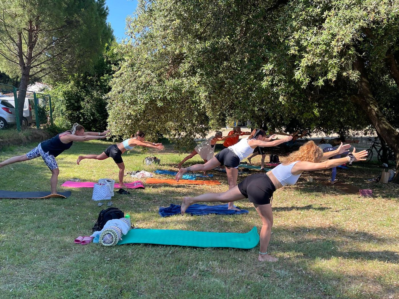 Summer yoga class holding a balancing posture on the grass
